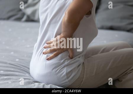 Ältere Frau hält Hand in Lendenwirbelsäule fühlt schwere Rückenschmerzen Nahaufnahme Stockfoto