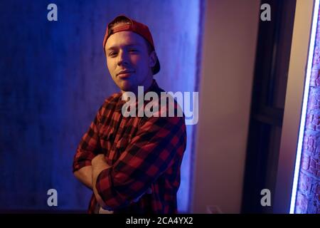 Gerissen genial Kerl mit gefalteten Armen Blick auf die Kamera drinnen. Street-Stil, Rap, DJ-Konzept Stockfoto