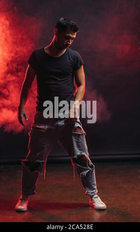 Junge kräftige männliche Tanz isoliert über rot rauchigen Raum, tragen Casual Wear. Street Dance Konzept Stockfoto