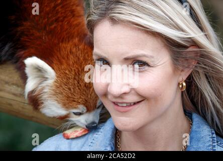 Countryfile Moderatorin Helen Skelton füttert einen roten Panda während eines Besuchs im Yorkshire Wildlife Park in Doncaster, um zwei neue erweiterte Tierreservate zu eröffnen: Erleben Sie Äthiopien und Himalayan Pass, wo Besucher Hyänen, Gelada Affen, Rote Pandas und glatt beschichtete Otter sehen können. Stockfoto