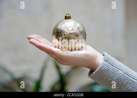 Nahaufnahme der Frau Hand zeigt eine goldene weihnachtskugel Stockfoto