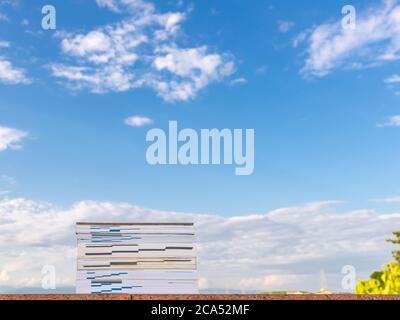 Bücher auf einer roten Steinmauer gegen einen schönen blauen Himmel mit weißen Wolken gestapelt Stockfoto