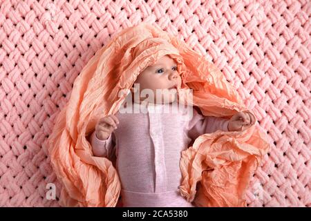 Zwei Monate altes Baby im pinken Anzug auf einem gestrickten Karabinett Stockfoto