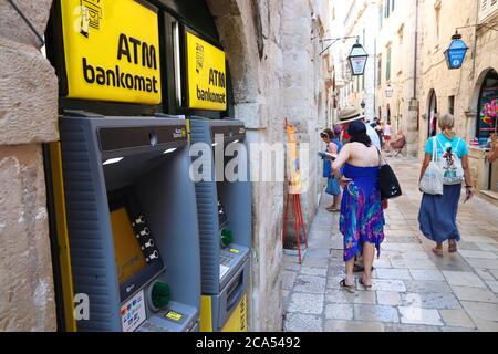 DUBROVNIK, KROATIEN - 26. JULI 2019: Touristen gehen an Geldautomaten an einer Einkaufsstraße in der Altstadt von Dubrovnik, die zum UNESCO-Weltkulturerbe gehört. Stockfoto