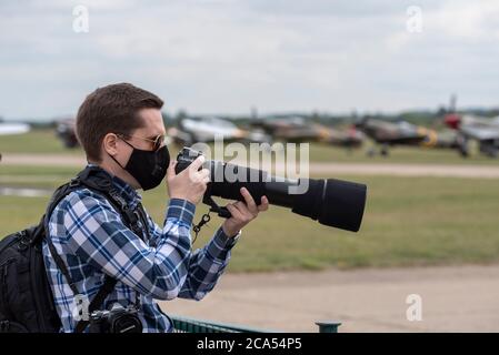 Imperial war Museum Duxford, Cambridgeshire, Großbritannien. August 2020. Nach einer langen Stilllegung durch die COVID-19 Coronavirus-Sperre öffnete das Museum am 1. August wieder seine Türen für Besucher. Heute hat das Museum seine erste Luftvorstellungsveranstaltung abgehalten – mit dem Titel A Showcase Day. Es war eine vorab gebuchte Ticket-only-Veranstaltung mit stark reduziertem Besucherlimit, und die Besucher mussten strenge Richtlinien einhalten, wenn sie die Innenausstattungen betraten. Ein Fotograf mit Weitwinkelobjektiv und Gesichtsmaske Stockfoto