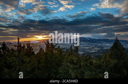 Dramatischer Libeerc Sonnenuntergang Himmel mit beleuchteten Wolken in den Bergen. Dunkelschwarze Silhouette von Bergrücken und Jested Sender Turm an der Bott Stockfoto