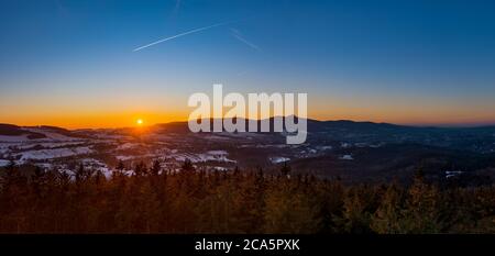 Dramatischer Libeerc Sonnenuntergang Himmel mit beleuchteten Wolken in den Bergen. Dunkelschwarze Silhouette von Bergrücken und Jested Sender Turm an der Bott Stockfoto