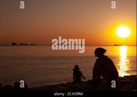 Ein Mann, der an einem Strand vor einem Sonnenuntergang steht Stockfoto