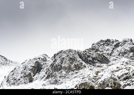 Felsformation mit besiedelter Schnee und Schneeflocken nach Sturm Ciara. In der Nähe von 'Devils Kitchen' in Wales. Stockfoto