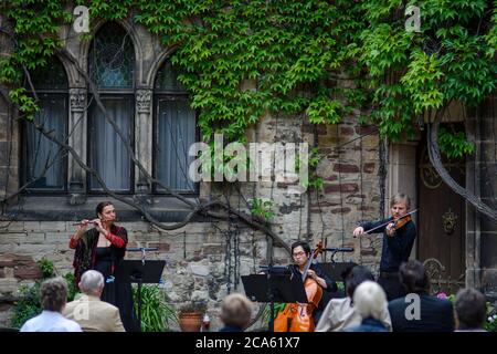 Wernigerode, Deutschland. August 2020. Barbara Toppel (l-r), Jaehyun Han und Alexey Naumenko vom Philharmonischen Kammerorchester Wernigerode spielen im Hof des Schlosses Wernigerode für Teilnehmer einer Soiree. Aufgrund der Ausbreitung des Coronavirus musste das jährliche Burgfest in seiner ursprünglich angekündigten Form abgesagt werden. Jetzt gibt es noch bis zum 29. August 2020 Soirees im Schlosshof und samstags Konzerte im Marstall.Quelle: Klaus-Dietmar Gabbert/dpa-Zentralbild/dpa/Alamy Live News Stockfoto