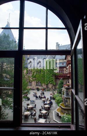 Wernigerode, Deutschland. August 2020. Blick durch ein Burgfenster auf eine Soiree im Hof der Burg Wernigerode mit Barbara Toppel (l-r), Jaehyun Han und Alexey Naumenko vom Philharmonischen Kammerorchester Wernigerode. Aufgrund der Ausbreitung des Coronavirus musste das jährliche Burgfest in seiner ursprünglich angekündigten Form abgesagt werden. Bis zum 29. August 2020 finden im Schlosshof Soirees statt und samstags finden Konzerte im Marstall statt.Quelle: Klaus-Dietmar Gabbert/dpa-Zentralbild/dpa/Alamy Live News Stockfoto