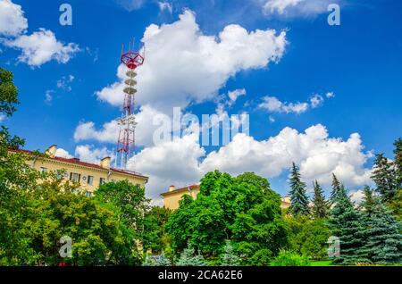 Fernsehturm hinter dem Gebäude in den grünen Bäumen Park im historischen Zentrum der Stadt Minsk, blauer Himmel weiße Wolken am sonnigen Sommertag, Republik Weißrussland Stockfoto