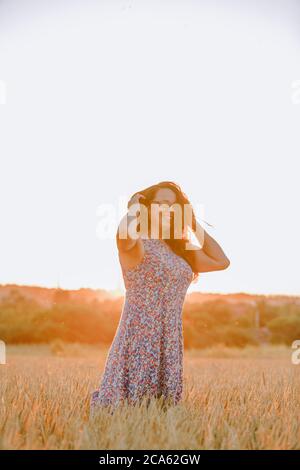 Schöne reife Frau in Sundress auf Weizenfeld bei Sonnenuntergang Stockfoto