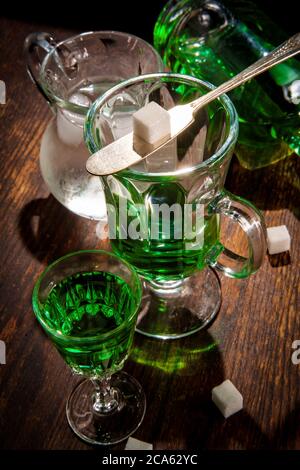 Grüner Absinthlauge im Glas mit Eiswasser zum Übergießen des Zuckerwürfels Stockfoto