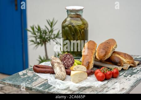 Stilvoller rustikaler Picknicktisch mit hausgemachten Salami, Wurst, Käse und Brot darauf, zusammen mit einigen frisch gepflückten Tomaten und grünen Paprika und Stockfoto