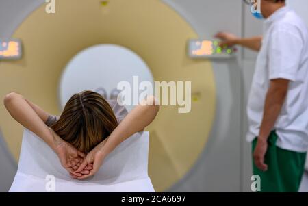 40-50 Jahre alte Frau betritt einen CT-Scanner zur Untersuchung in einem Krankenhaus. Selektive Fokussierung auf den Patientenkopf im Vordergrund. Stockfoto