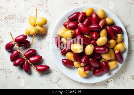 Rote und gelbe frische Datteln Obst in weißen Teller Stockfoto