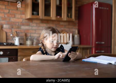 Smart kleines Mädchen mit Handy zu Hause Küche Stockfoto