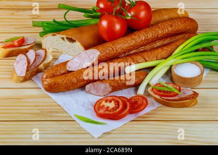 Krakowska polieren kielbasa mit Gemüse und Salz auf Holztisch. Stockfoto