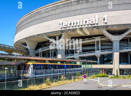 Ein CDGVAL-Flughafenshuttle fährt am Bahnhof am Fuß des runden Betongebäudes des Terminals 1 des Flughafens Paris-Charles de Gaulle ab. Stockfoto