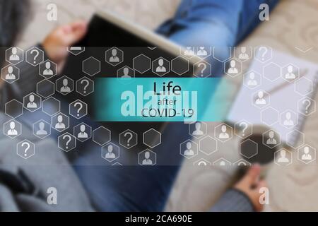 Leben nach СOVID-19 auf dem Touchscreen mit einem verschwommenen Hintergrund einer Person mit einem Tablet. Genesung und Leben nach dem Coronavirus Stockfoto