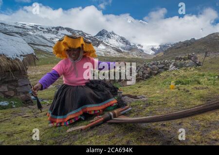 Eine quechua-Frau in den hohen Anden webt Alpakawolle zu Kleidungsstücken, wie es traditionell seit vielen Generationen geschieht. Stockfoto