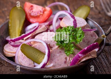 bayerischer Wurstsalat auf dunklem Holz Stockfoto