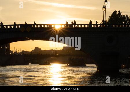 Silhouette der Brücke bei Sonnenuntergang in Paris, Frankreich. Brücke genannt Pont au Change mit Reflexion auf dem Wasser. Menschen winken mit der Hand. Blick vom Boot aus. Stockfoto