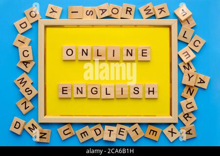 Holzbuchstaben mit Phrase online englisch in gelbem Rahmen auf blauem Hintergrund. Stockfoto