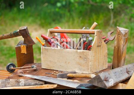 Holzkiste mit verschiedenen Vintage-Arbeitswerkzeugen. Alte Tischlerkiste mit Werkzeugen auf Holztisch. Stockfoto