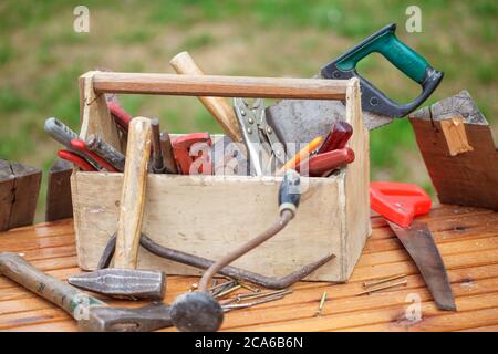 Holzkiste mit verschiedenen Vintage-Arbeitswerkzeugen. Alte Tischlerkiste mit Werkzeugen auf Holztisch. Stockfoto