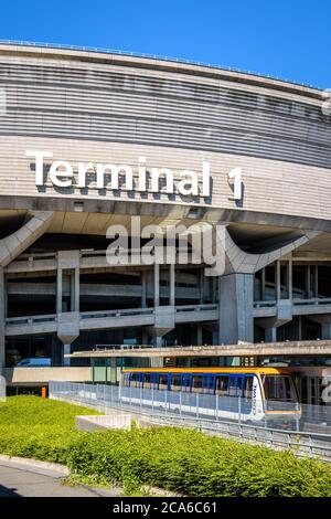 Ein CDGVAL-Flughafenshuttle fährt am Bahnhof am Fuß des runden Betongebäudes des Terminals 1 des Flughafens Paris-Charles de Gaulle ab. Stockfoto