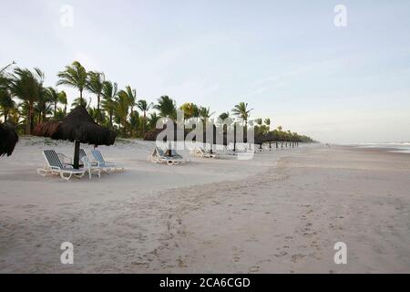 Liegestühle und Hütten am Strand in Una, Bahia, Brasilien Stockfoto