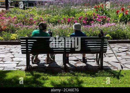 Zwei ältere Damen sitzen auf einer Bank im Karhupuisto Park im Kallio Bezirk in Helsinki, Finnland Stockfoto