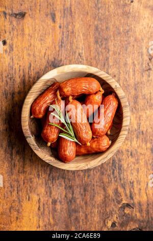 Mini Salami Würste in Schüssel auf Holztisch. Draufsicht. Stockfoto