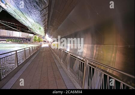 Chicago, Illinois - August 8, 2019 - Reflektierende gebogene Metallwände und Decke der Chicago Riverwalk Unterführung unter Brücke überqueren Fluss. Stockfoto