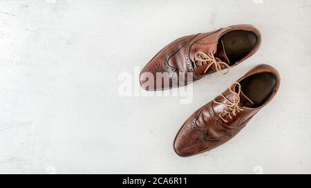 Overhead Shot, Paar alte braune Schuhe auf weißem Brett, breites Banner mit Platz für Text links Stockfoto