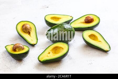 Avocados halbieren, eine ganze Birne in der Mitte, auf weißem Arbeitsbrett. Stockfoto