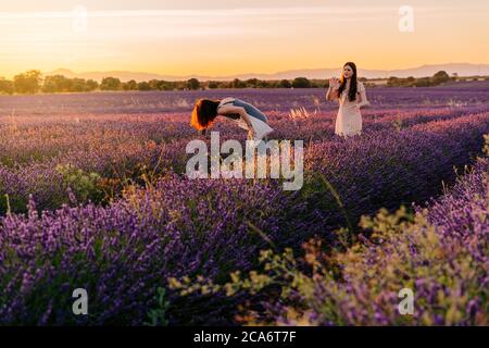 Zwei Freunde haben Spaß und machen Fotos mit ihrem Handy in einem Feld von blühenden Lavendel, während des Sonnenuntergangs. Urlaub in der Natur, Spanien Stockfoto