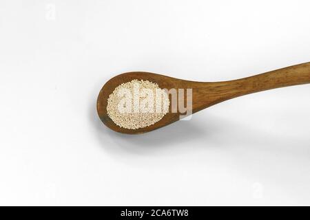 Instant Hefe isoliert auf weiß. Trockene Hefe in Holzlöffel auf weißem Hintergrund Stockfoto