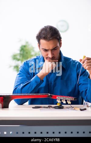Junger Mann Reparatur der Gitarre Stockfoto