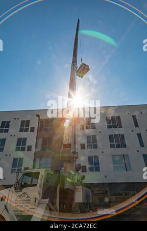 Denver, Colorado - Sonnenkollektoren und andere Geräte für eine Solaranlage werden an die Spitze eines neuen erschwinglichen Wohngebäudes gehoben. Das so Stockfoto