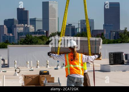 Denver, Colorado - Sonnenkollektoren und andere Geräte für eine Solaranlage werden an die Spitze eines neuen erschwinglichen Wohngebäudes gehoben. Das so Stockfoto