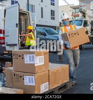 Denver, Colorado - Sonnenkollektoren und andere Geräte für eine Solaranlage sind für einen Aufzug an die Spitze eines neuen erschwinglichen Gehäuse bui vorbereitet Stockfoto