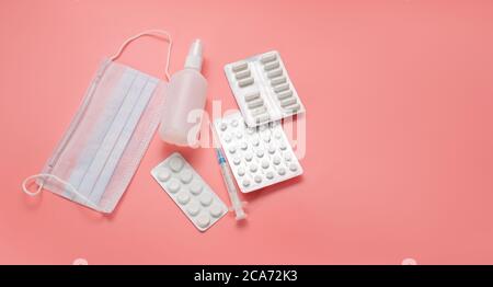 Eine Reihe von verschiedenen medizinischen Gegenständen. Spritze, Maske, Tabletten und Desinfektionsmittel auf rosa Hintergrund. Mittel zur Vorbeugung und Behandlung von Coronaviren. Stockfoto