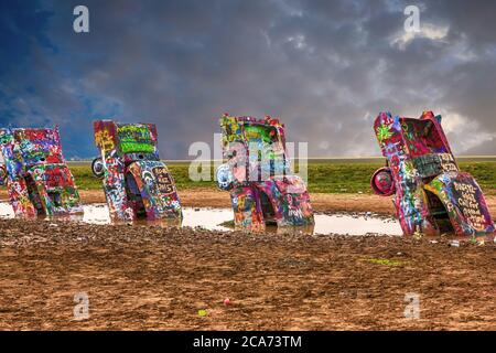 Cadillac Ranch mit seinen hoch lackierten Fahrzeugen in der Mitte eines schlammigen Feld etwas außerhalb Amarillo, Texas Stockfoto