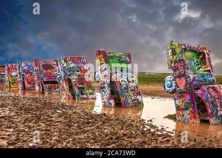 Cadillac Ranch mit seinen hoch lackierten Fahrzeugen in der Mitte eines schlammigen Feld etwas außerhalb Amarillo, Texas Stockfoto