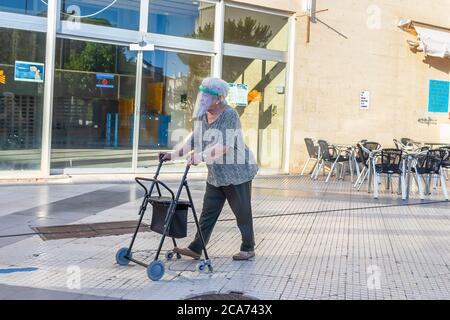 Punta Umbria, Huelva, Spanien - 10. Juli 2020: Ältere Frau auf der Straße mit Schutzschild aus Kunststoff wegen covid-19. Neue Normalität in Spanien Stockfoto