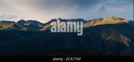 Die untergehende Sonne hebt Sturmwolken und Berggipfel hervor - ein Panorama der San Juan Mountains vom Molas Pass in Colorado Stockfoto