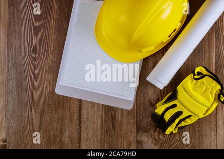 Architekt oder Ingenieur, der am Architekturmodus Blaupause im Büronotizblock auf gelbem Schutzhelm auf Hintergrund arbeitet. Stockfoto